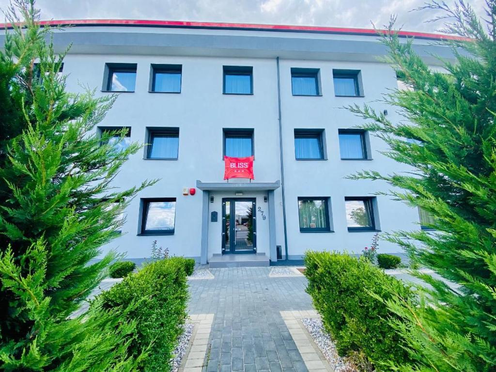 biały budynek z czerwonymi drzwiami i drzewami w obiekcie Hotel Bliss w mieście Roman