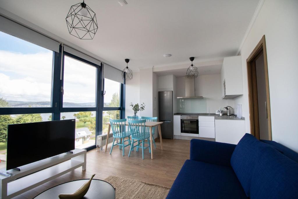ein Wohnzimmer mit einem blauen Sofa und einer Küche in der Unterkunft Mar de Sada in Sada