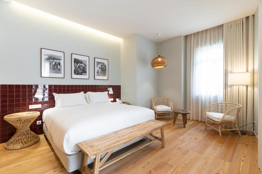 a bedroom with a large white bed and a bench at Quinta de São Luiz The Vine House in Tabuaço