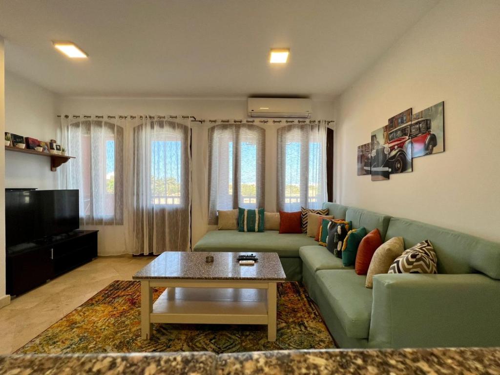 sala de estar con sofá verde y mesa en Taj Home, Amazing pool and lagoon view 2bedrooms apartment, en Hurghada