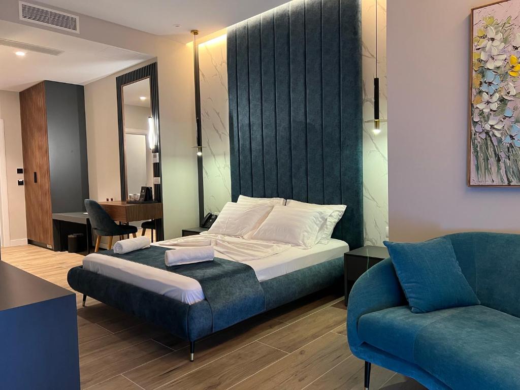 um quarto com uma cama e um sofá azul em Domus Hotel & Apartments em Shëngjin