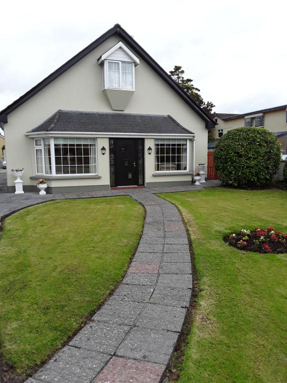 a white house with a walkway in front of a yard at Greenmount Accommodation in Killarney