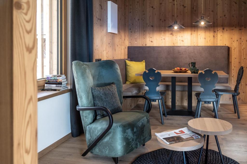 ein Wohnzimmer mit einem grünen Stuhl und einem Tisch in der Unterkunft Oberfallerhof Apartment Ummi in Barbian
