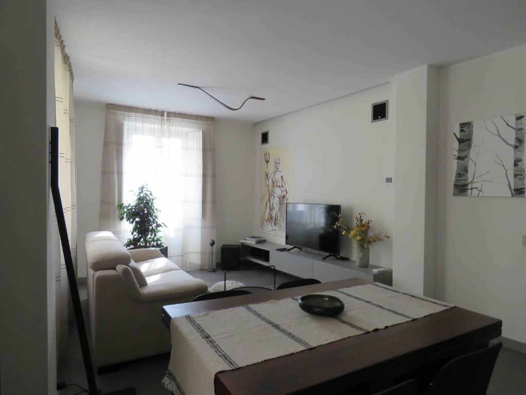 ein Wohnzimmer mit einem TV, einem Sofa und einem Tisch in der Unterkunft Les fleuves - Doire - Alloggio ad uso turistico - VDA - AOSTA - n 116 in Aosta