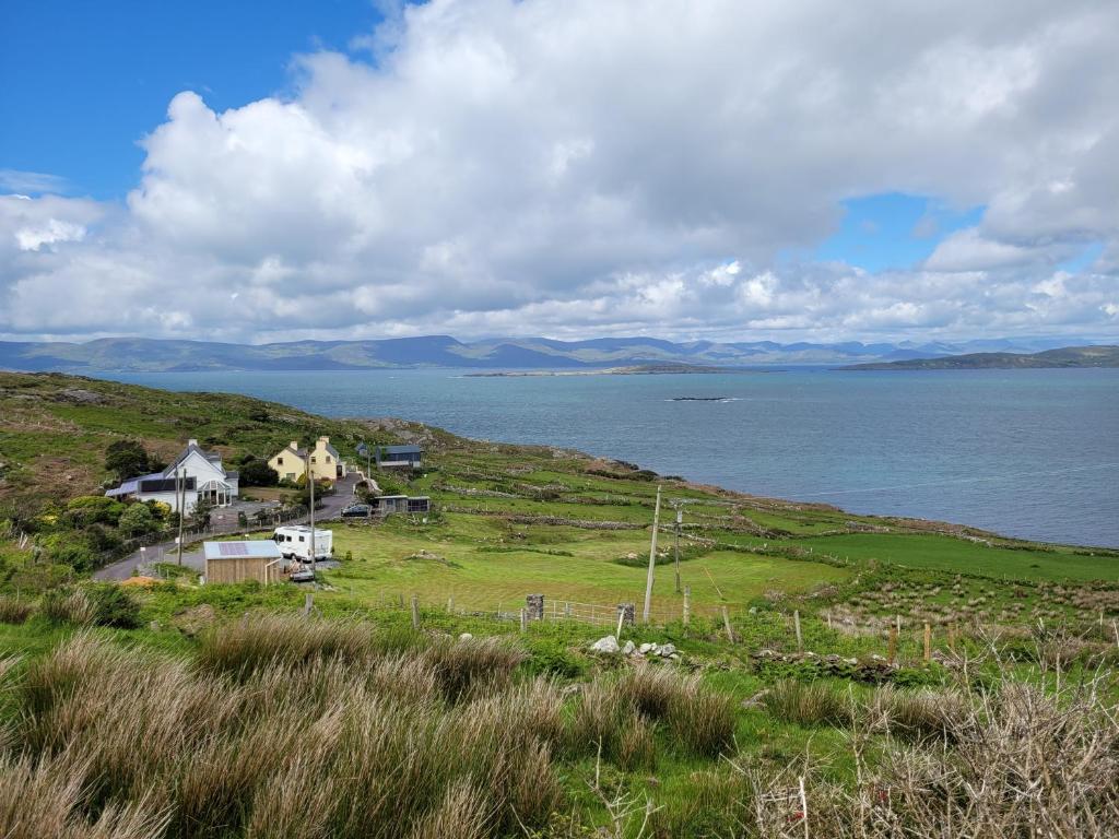 ein Haus auf einem Hügel neben einem Wasserkörper in der Unterkunft Anam Sona SeaView B&B in Caherkeen