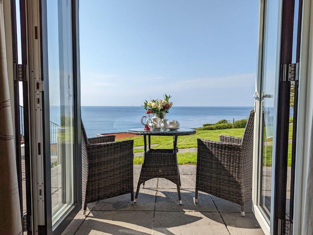 a table and chairs on a balcony with a view of the ocean at Sunset Surf - Mount Brioni in Downderry