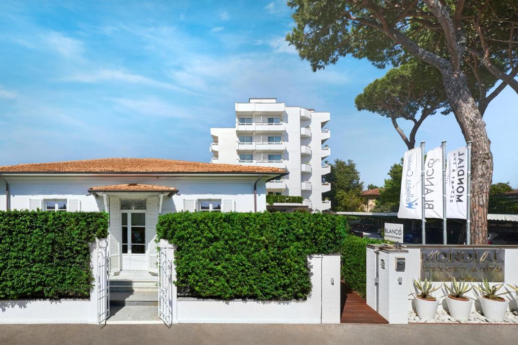 un bâtiment blanc avec des plantes devant lui dans l'établissement Mondial Resort & Spa, à Marina di Pietrasanta