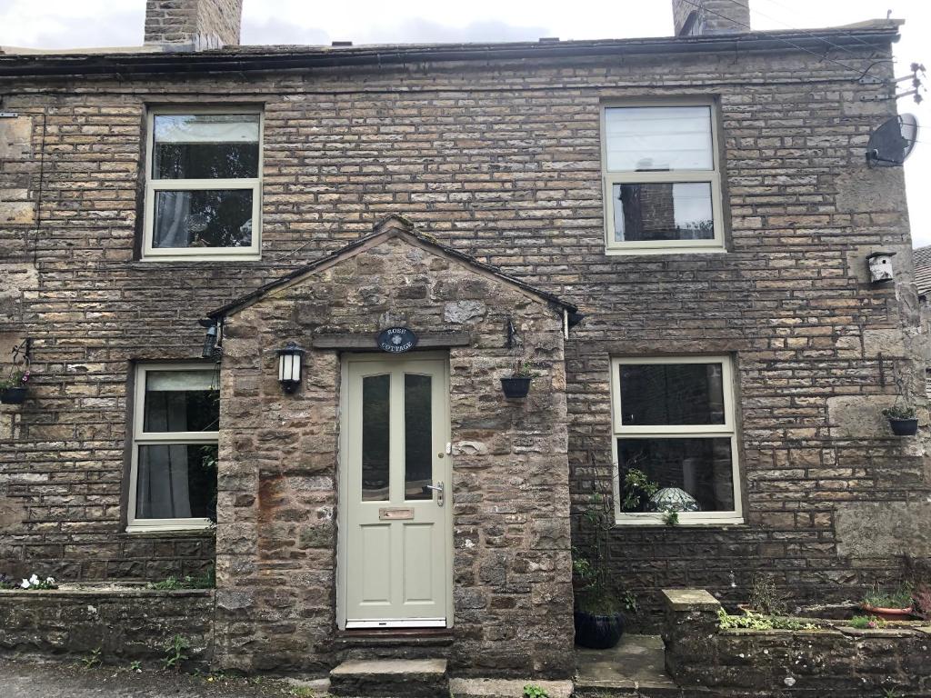 a brick house with a white door and windows at Rose Cottage. Family home on the river in Hawes