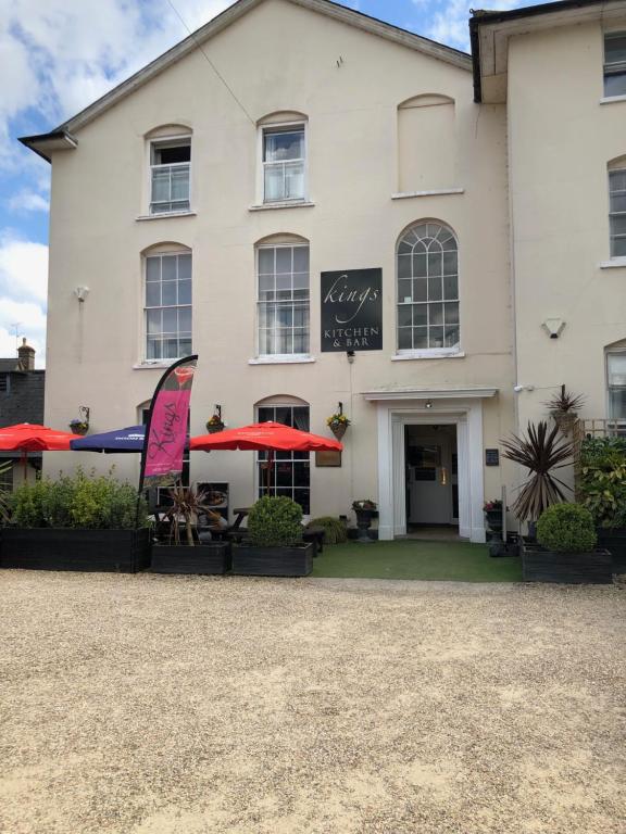 a white building with tables and umbrellas in front of it at Kings Lodge in Newmarket