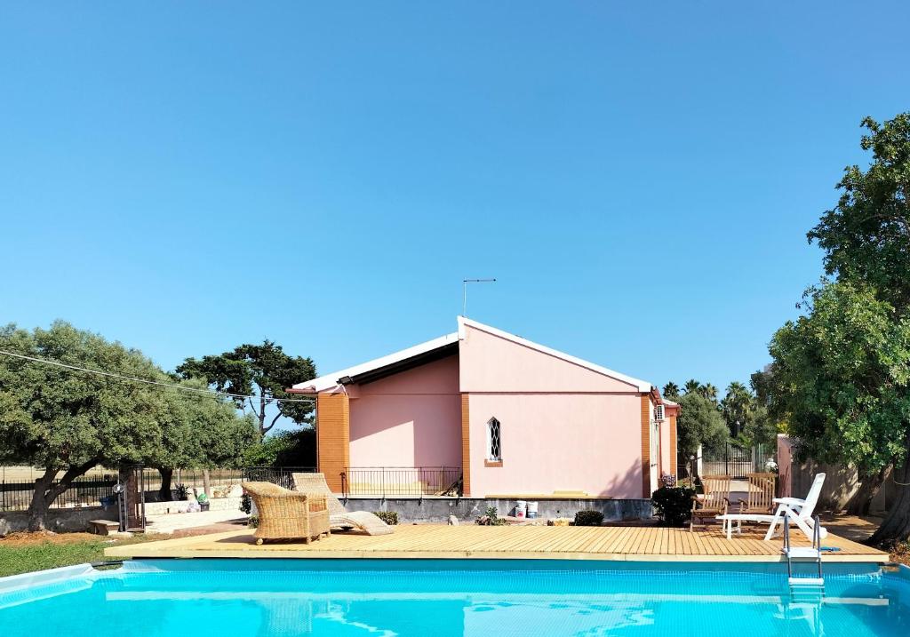 a house with a swimming pool in front of a building at La Casa di Ludovica, Punta della Mola in Siracusa