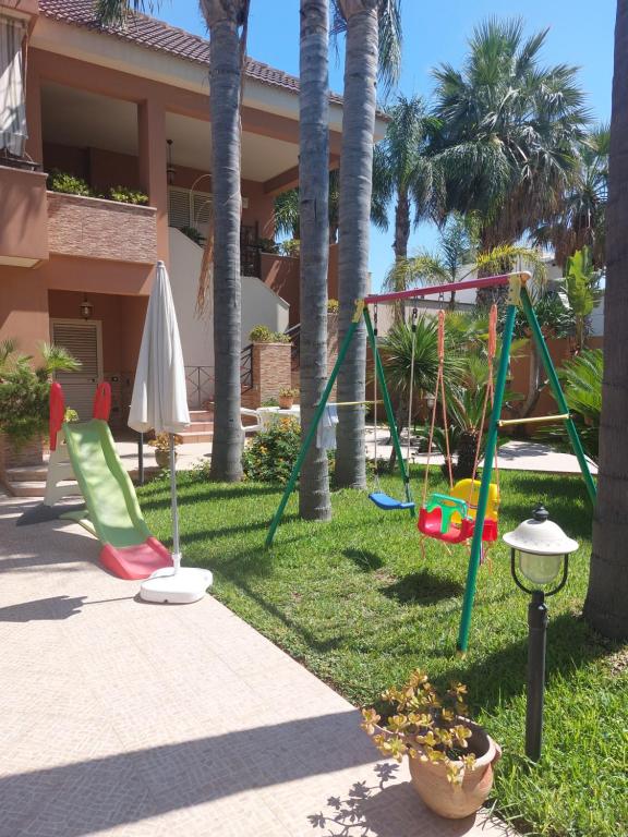 a yard with a swing set and palm trees at Casa con giardino Giacalone in Mazara del Vallo