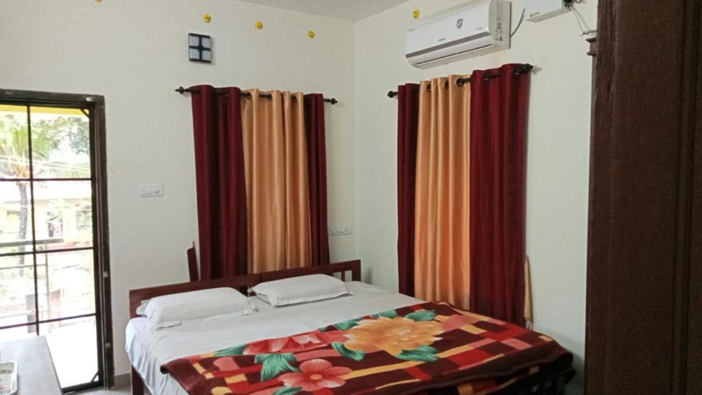 a bedroom with a bed and curtains and a window at Tejus Home Stay in Alleppey