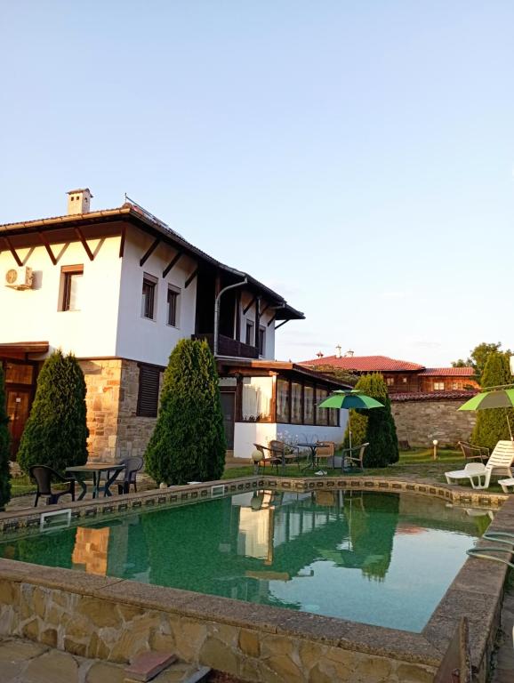 a house with a swimming pool in front of a building at Toncho's Guest House for 16 guests in Arbanasi