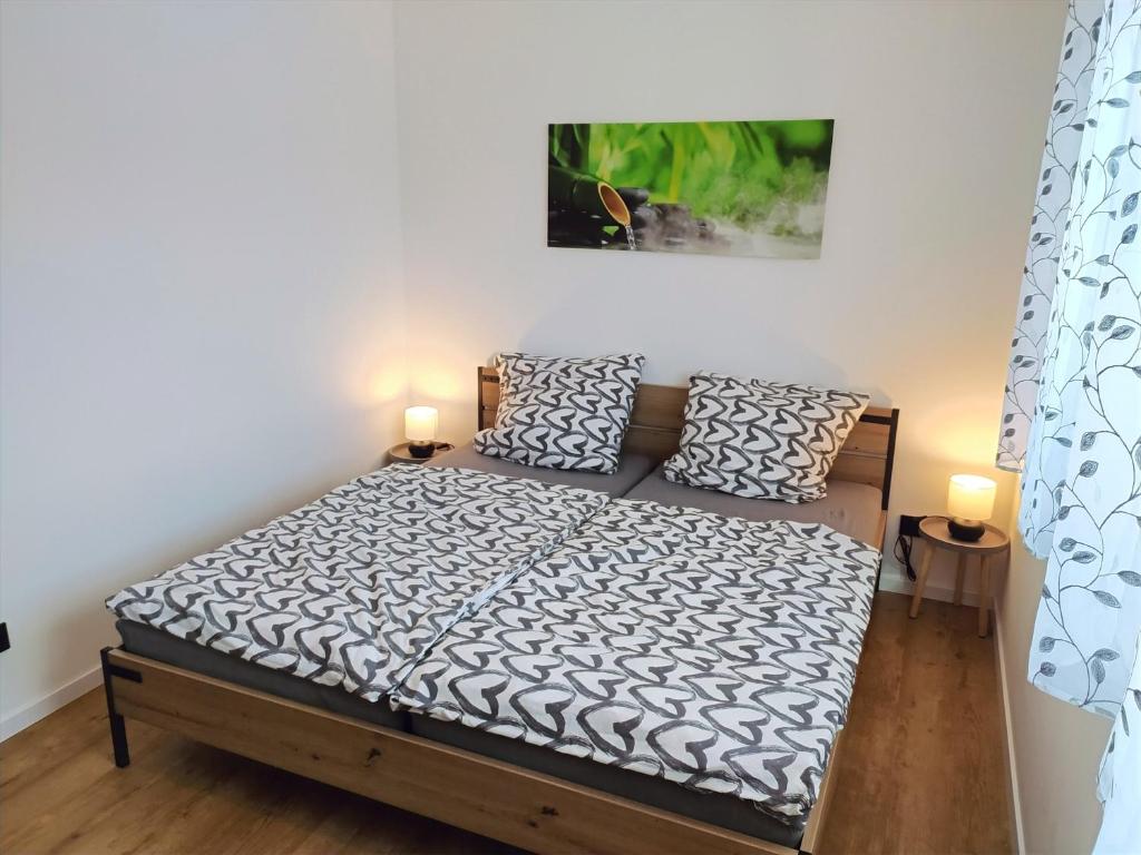 1 dormitorio con 1 cama con 2 lámparas en FeWo Wildflecken - Ferienwohnung Rhön Neubau 2021 en Wildflecken