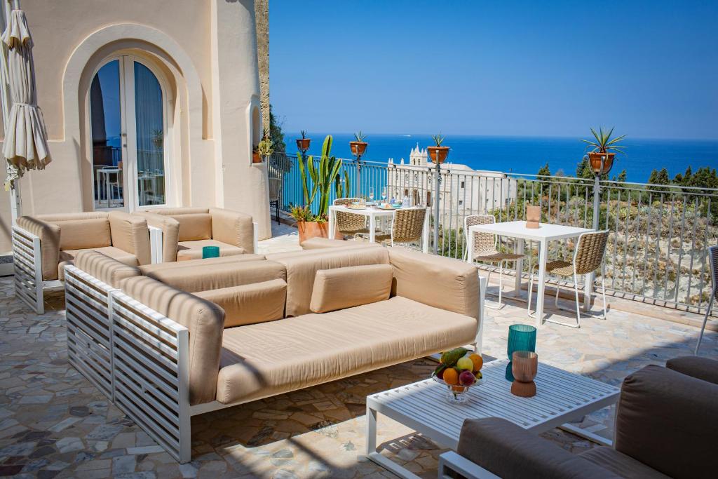 a patio with a couch and tables and the ocean at La Dolce Vita a Tropea in Tropea