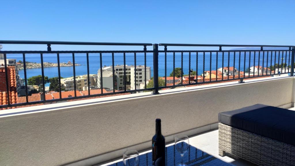 a bottle of wine sitting on a balcony with a view at Apartments Juranovic in Makarska