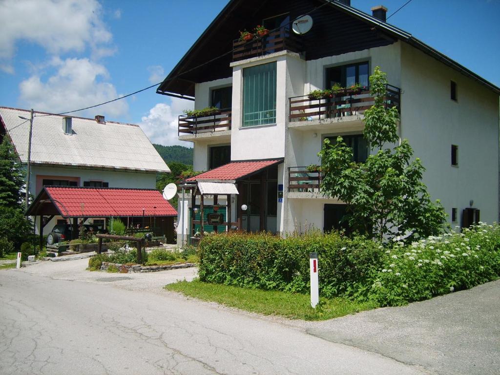 a white building with red roofs on a street at Guest House Raukar in Crni Lug