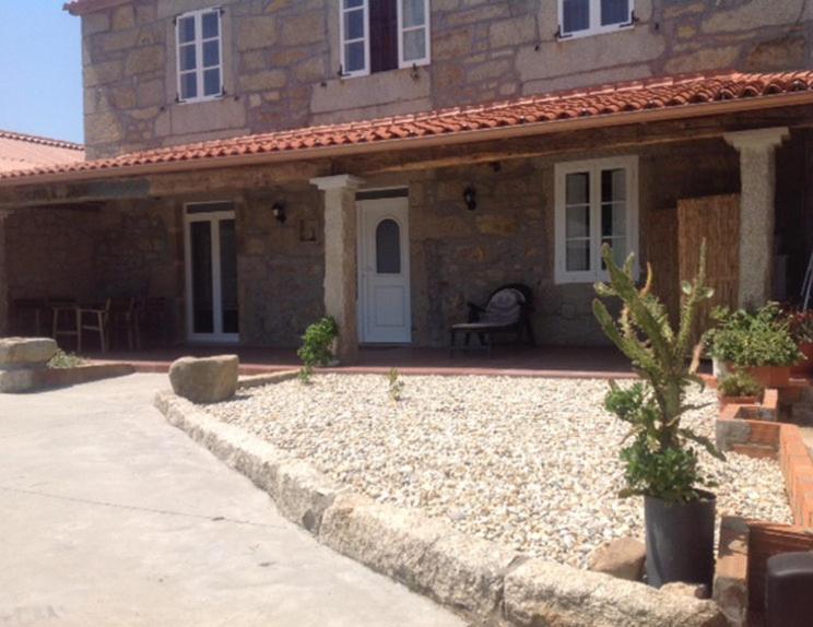 een stenen huis met een bankje ervoor bij Casa do Rei in Boiro