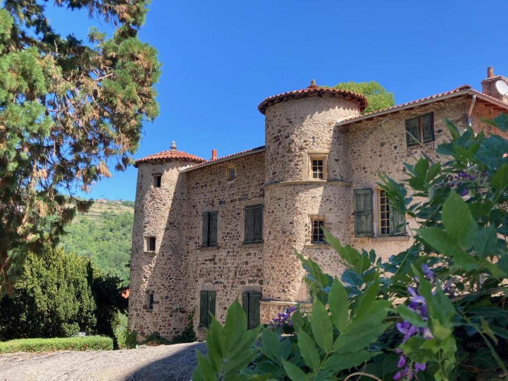 un vieux bâtiment en pierre avec des arbres au premier plan dans l'établissement Chateau Paysan ecolobio de Durianne, à Le Monteil