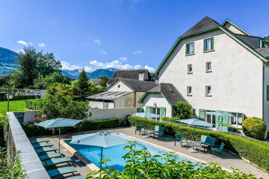 ein Hotel mit einem Pool, Stühlen und Sonnenschirmen in der Unterkunft Auberge de l'Étable in Montory