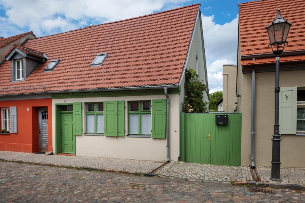 Atelierhaus auf der Insel Werder mit Garten, W-Lan und Netflix في Gallin: منزل بأبواب خضراء وسقف احمر