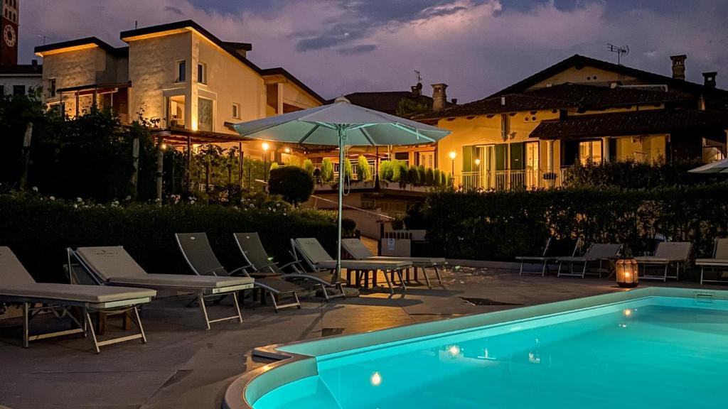 a pool with chairs and an umbrella next to a house at La Rosa Gialla Bio Apartments & rooms in Barolo