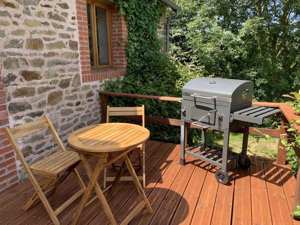 - un barbecue, une table et des chaises sur une terrasse dans l'établissement Les Rouges Terres Gites - La Vieille Grange, à Saint-Amand