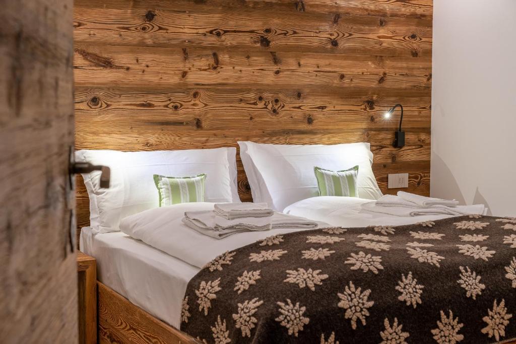a bedroom with a large bed with white sheets at Chalet Ines in Vodo Cadore