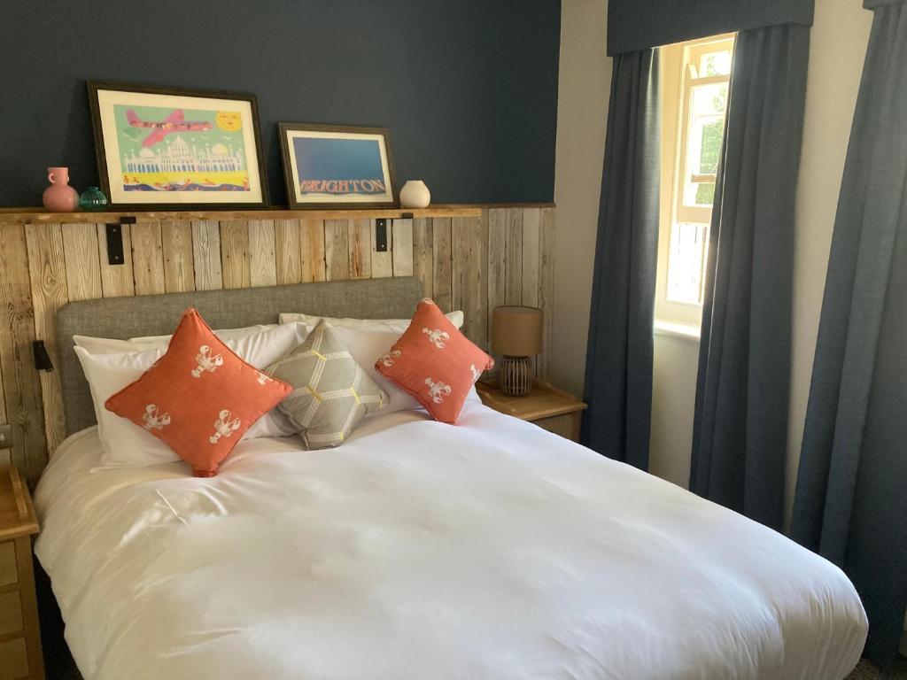 a white bed with orange pillows in a bedroom at Downs Hotel in Stanmer