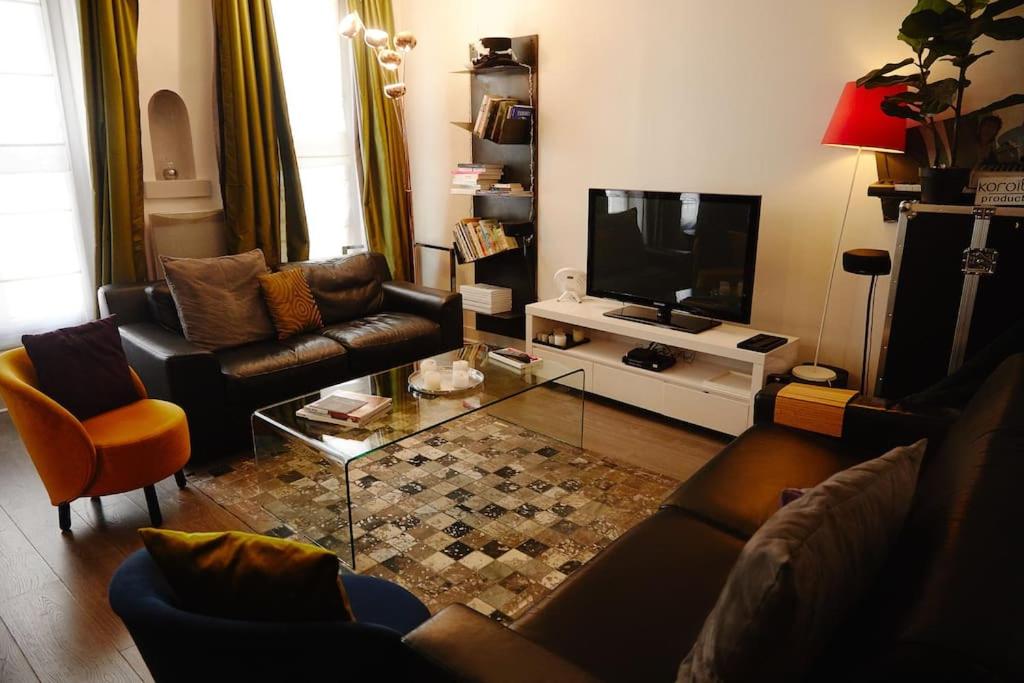 a living room with couches and a television at Cozy 2-Pièces au Coeur du Haut-Marais in Paris
