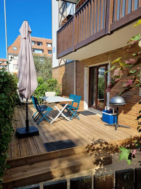 un patio avec un parasol, une table et des chaises dans l'établissement Appartement VILLERS SUR MER, à Villers-sur-Mer