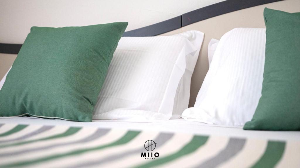 a bed with green and white pillows on it at MIIO HOTEL in San Vincenzo
