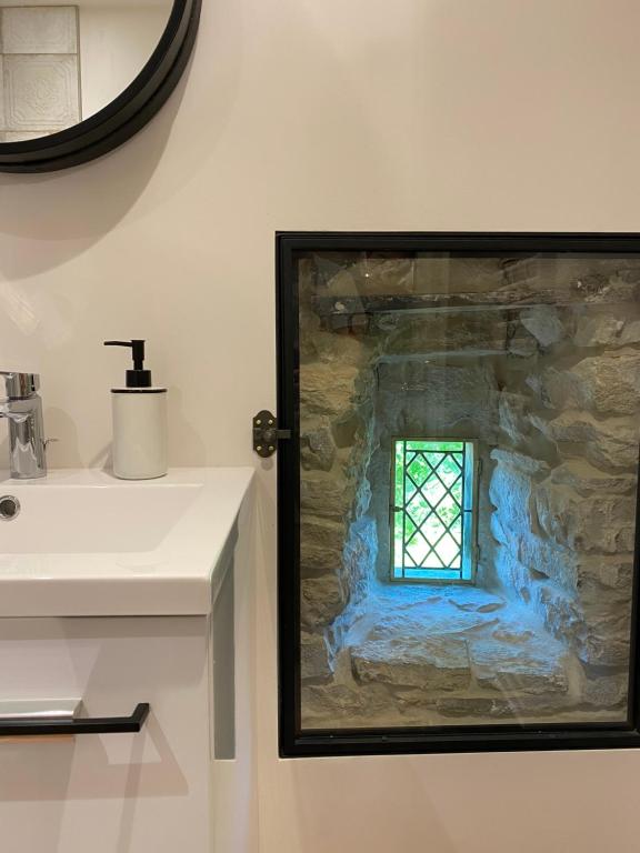 ein Bild eines Fensters in einer Steinwand neben einem Waschbecken in der Unterkunft Logement entier Noyers - L'Appart des Anges 2 in Noyers-sur-Serein