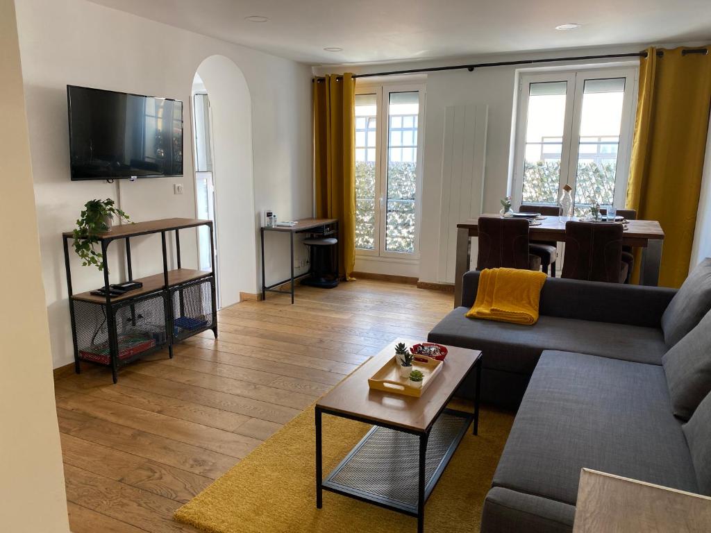 uma sala de estar com um sofá e uma mesa em Le Roofound - Porte de Paris - Métro à 5min - Entrée personnelle em Charenton-le-Pont