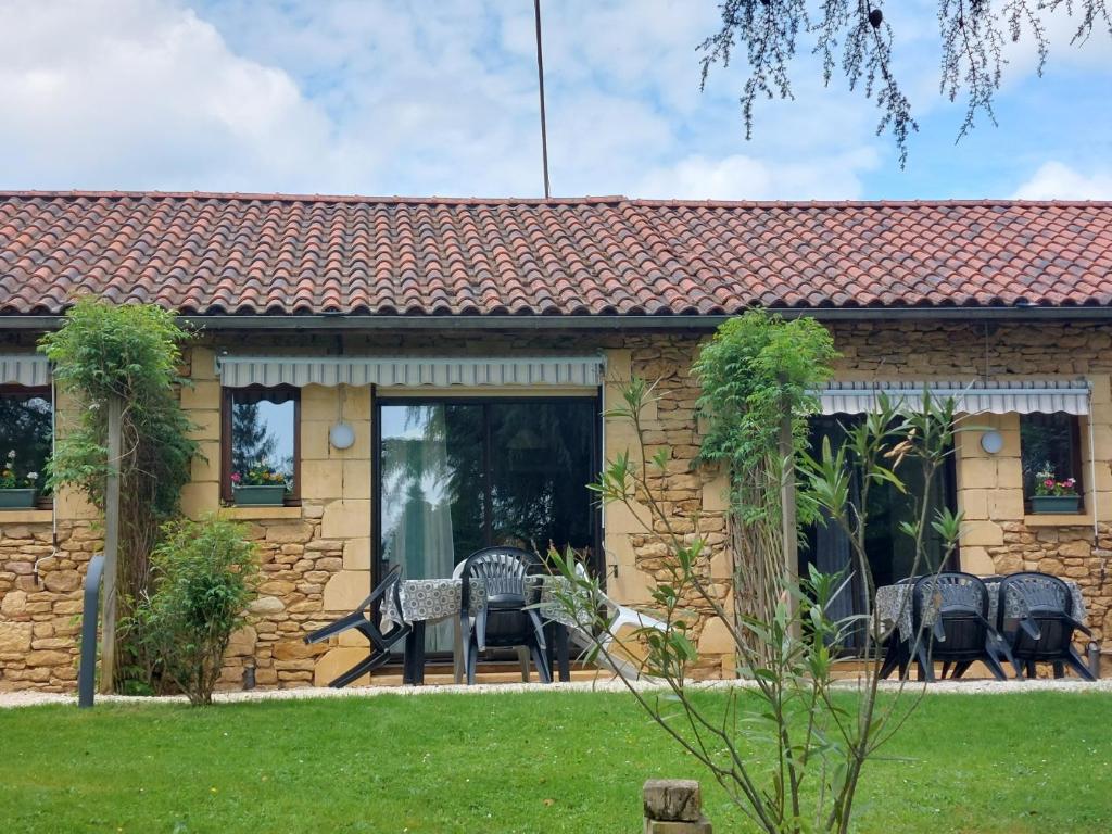 une maison en pierre avec une terrasse et une pelouse dans l'établissement GITE LE PARC A SARLAT Parking privé, à Sarlat-la-Canéda