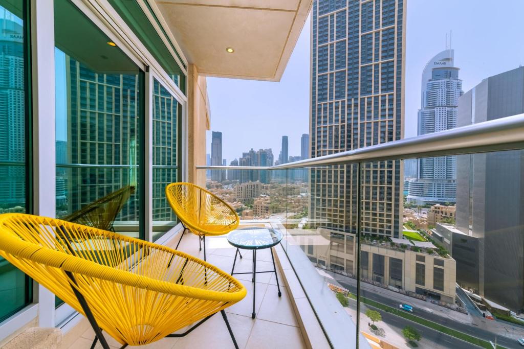 Un balcón con 2 sillas amarillas y una mesa. en Maison Privee - 5 Star Apt with 2BR in Downtown Dubai en Dubái