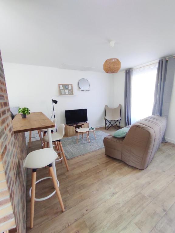 ein Wohnzimmer mit einem Sofa und einem Tisch in der Unterkunft Les Nuits Bonneuilloises Le Percheron in Breteuil