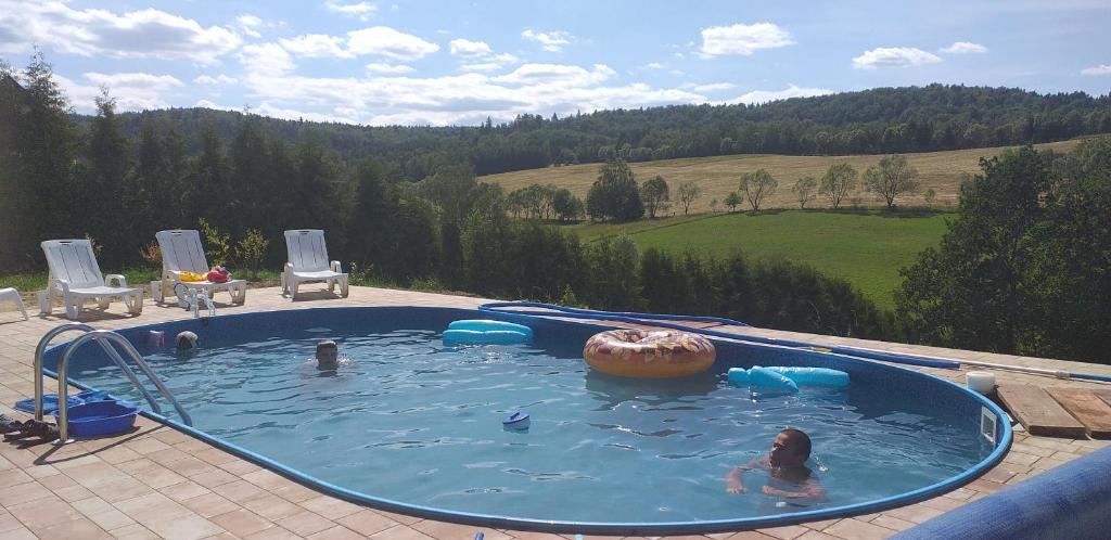 a girl in a swimming pool with a donut in the water at Domki WiliCamp in Polańczyk