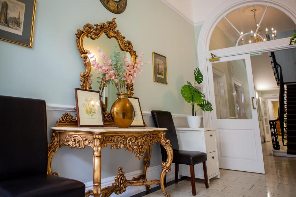 a table with a mirror and a vase with flowers on it at Marylebone Inn in London