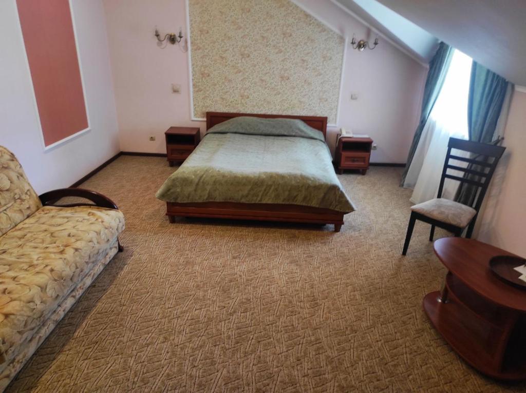 a bedroom with a bed and a couch and a chair at Готель Преміум in Lviv