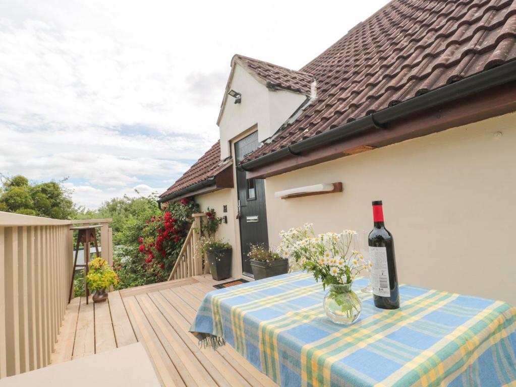 a bottle of wine sitting on a table on a deck at West Moor Cottage Annex in Martock