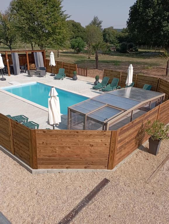 a swimming pool with a wooden deck and a swimming poolvisor at Les gîtes du petit Marcel in Soudan