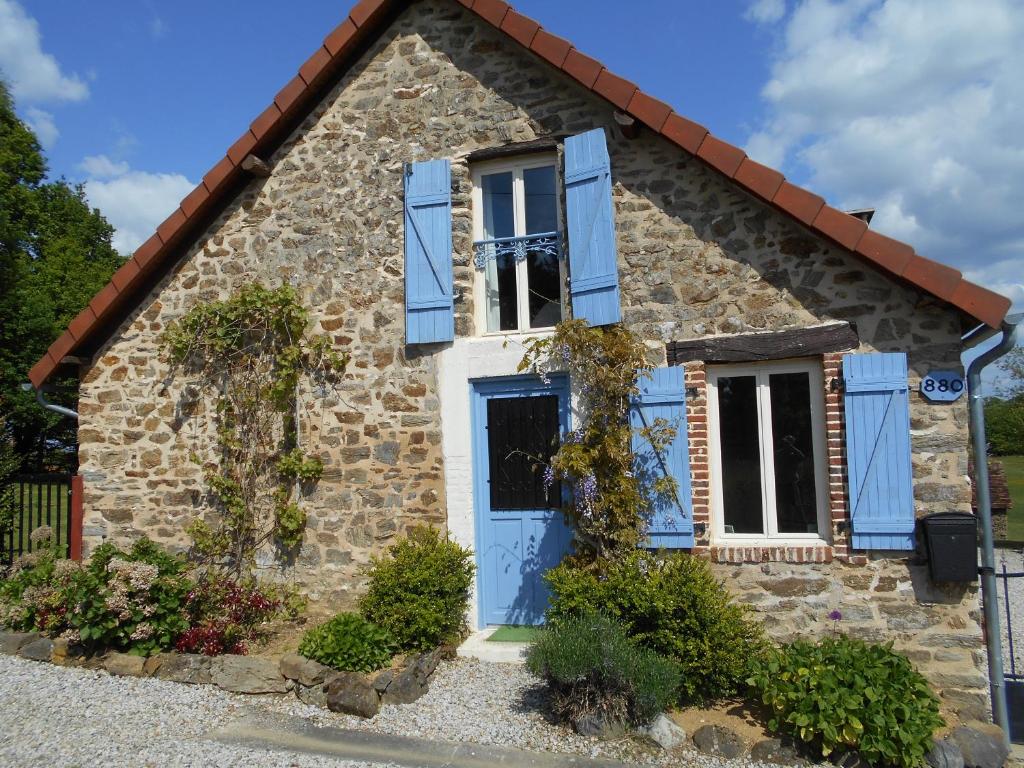 Una casa de piedra con persianas azules. en Les Landes Gîte, en Saint-Pardoux-Corbier