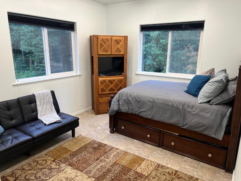 ein Schlafzimmer mit einem Bett und einem Sofa sowie zwei Fenstern in der Unterkunft Newly Remodeled spacious units, minutes from mountains, inlet, downtown and airport in Anchorage