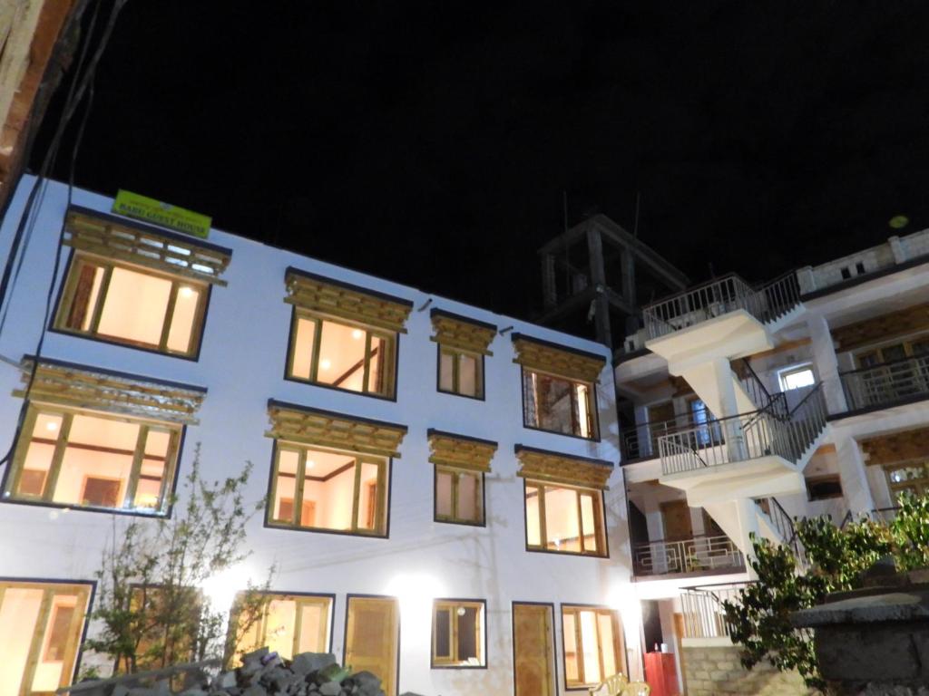 ein weißes Gebäude mit beleuchteten Fenstern in der Nacht in der Unterkunft Babu Guest House in Leh