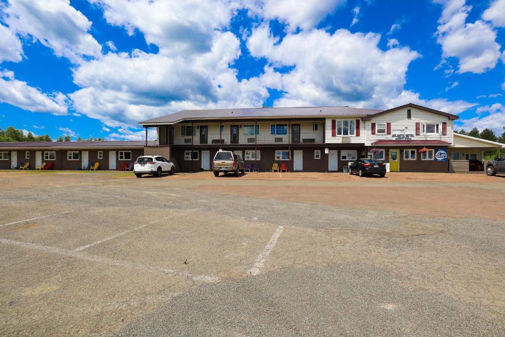 ein großes Gebäude mit Autos auf einem Parkplatz in der Unterkunft Atlantic Motel in Moncton