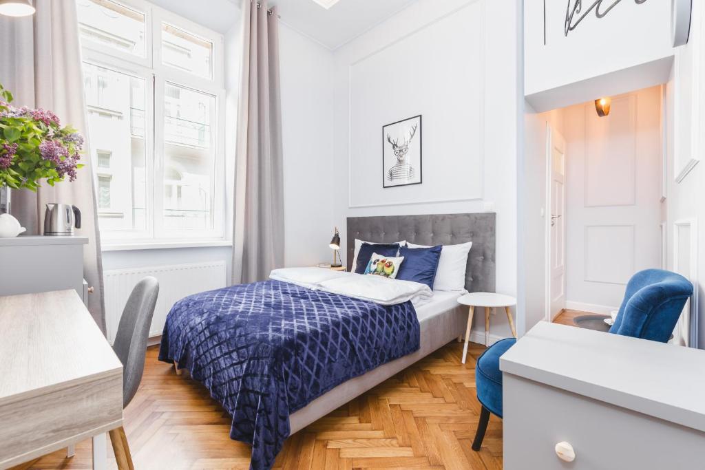 a small bedroom with a bed and a blue chair at Traveler's Best Choice - Old Town Guesthouse in Kraków