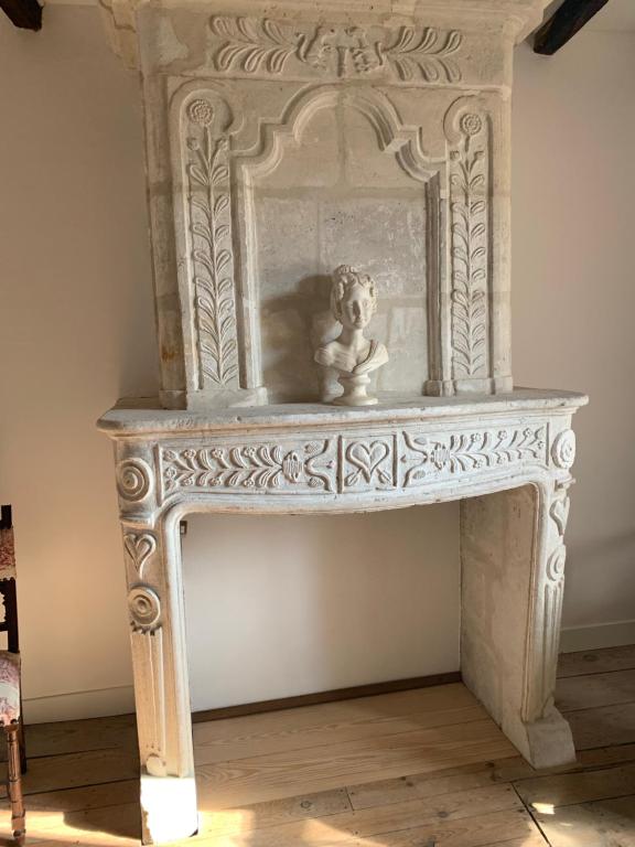 une cheminée en marbre blanc avec un ours en peluche assis sur elle dans l'établissement Le Doux Nid La Romantique, à Saint-Aulaye