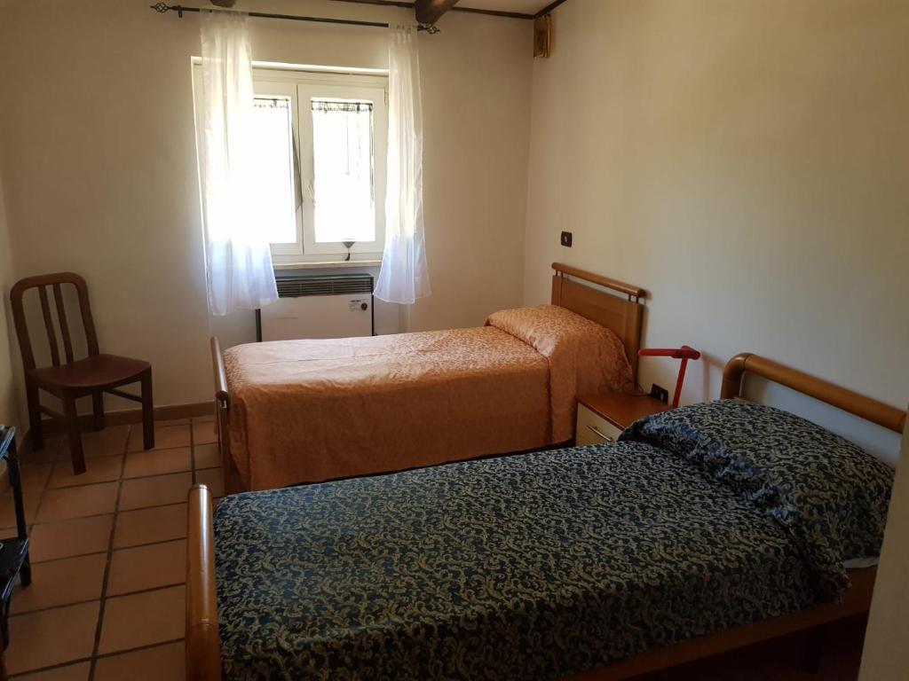pokój z dwoma łóżkami, krzesłem i oknem w obiekcie Chalet di montagna w mieście Trasacco