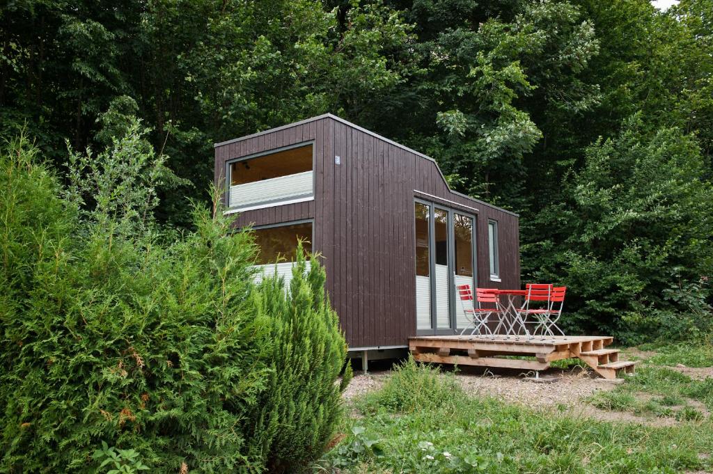 uma pequena cabana com duas cadeiras vermelhas na floresta em Tiny House Nature 3 - Green Tiny Village Harz em Osterode